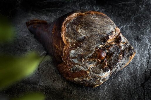 Photo produit, un magnifique jambon sur fond de pierre de la salaison Maison Alpin. Photographe à Annecy en Haute Savoie