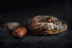 Photo produit, un magnifique jambon sur fond de pierre de la salaison Maison Alpin. Photographe à Annecy en Haute Savoie