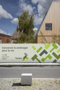 Conception de panneaux de chantier par un graphiste freelance à Annecy pour Tecam, bureau d'études en urbanisme et paysage. L'affiche présente un design moderne avec le slogan 'Concevoir & aménager pour la vie' et des éléments graphiques évoquent la nature et la construction.