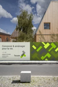 Conception de panneaux de chantier par un graphiste freelance à Annecy pour Tecam, bureau d'études en urbanisme et paysage. L'affiche présente un design moderne avec le slogan 'Concevoir & aménager pour la vie' et des éléments graphiques évoquent la nature et la construction.