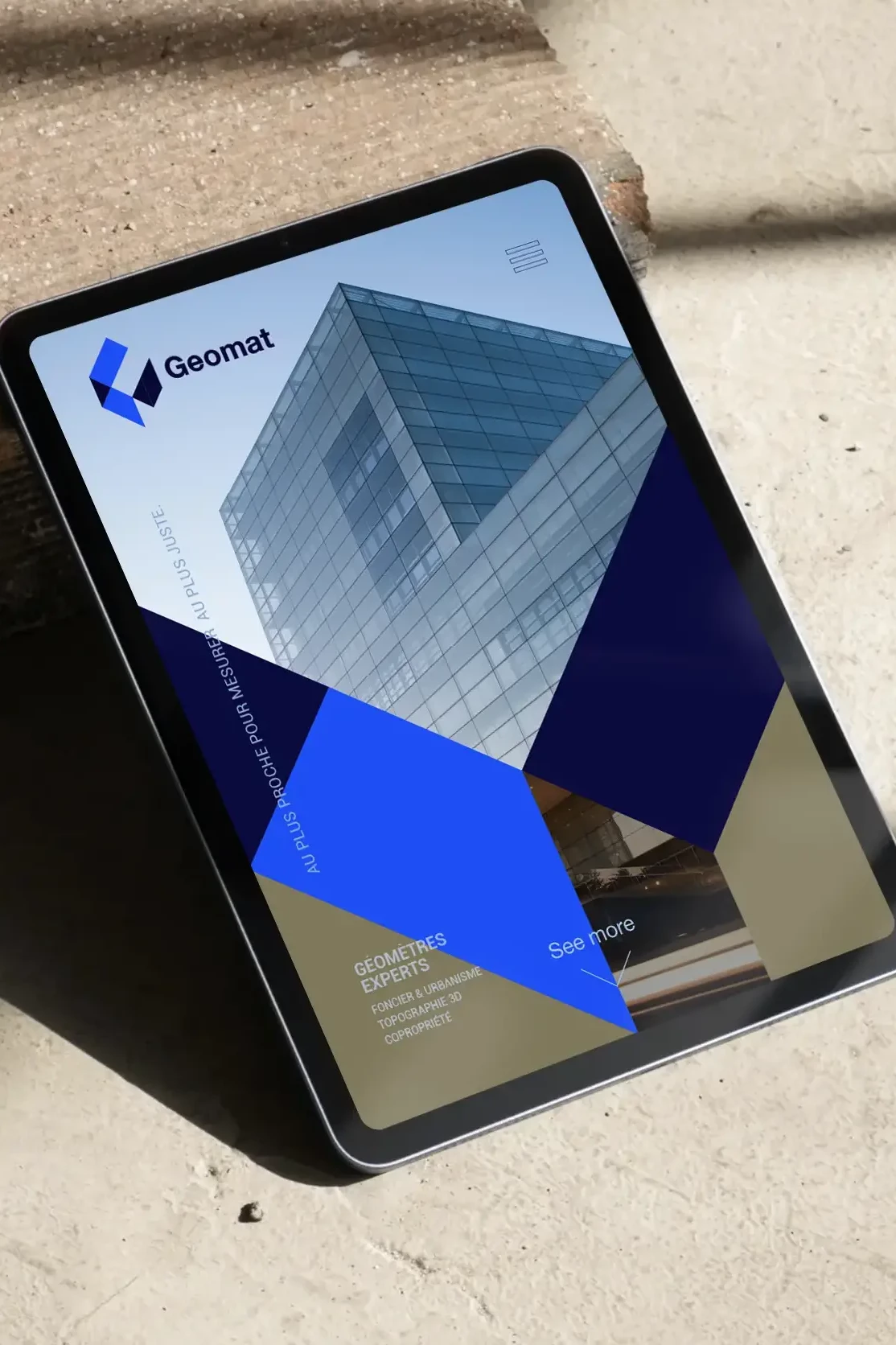 Conception de site web pour Geomat, réalisée par un graphiste freelance à Annecy, montrant une tablette avec un design moderne et professionnel pour une entreprise de construction.
